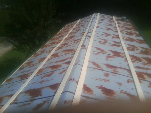 Rusted metal roof panels with new wood purlins before replacement in Greenville